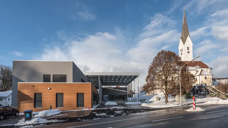 Gemeindezentrum Fraunberg im Schnee, dahinter der Kirchturm und eine alte Eiche