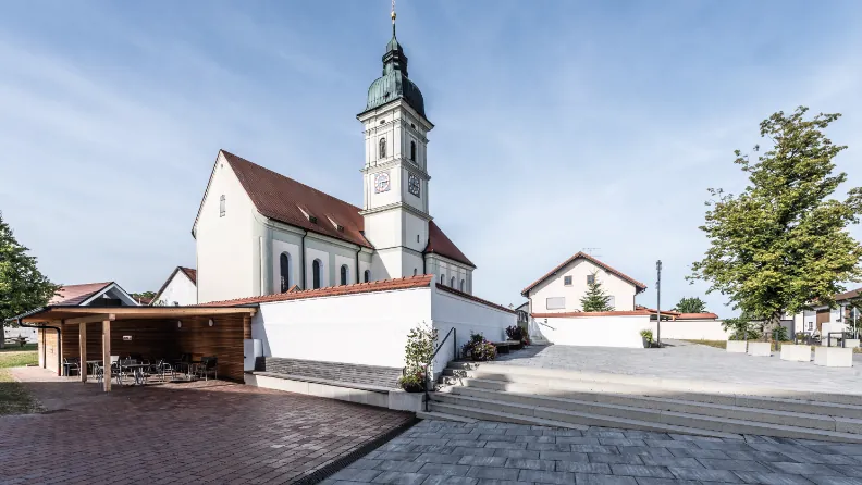 Neues Salettl aus Holz am gepflasterten Dorfplatz von Reichenkirchen, dahinter die Kirche