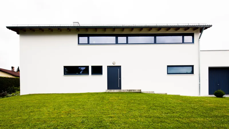 Aufgestocktes weißes Wohnhaus in Reisbach mit Fensterband unter dem flachen Dach